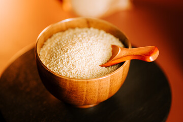 Couscous in a wooden bowl with a wooden spoon on a warm kitchen table