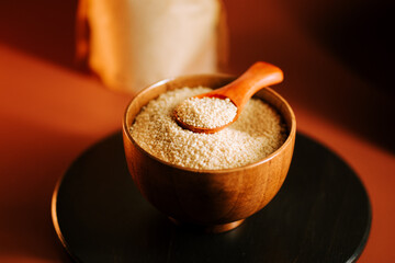 Couscous sits in a wooden bowl next to a spoon ready for meal preparation and cooking