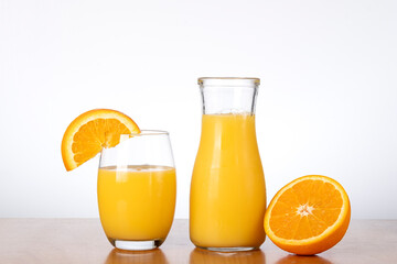 Fresh orange juice in glass and pitcher with orange slice