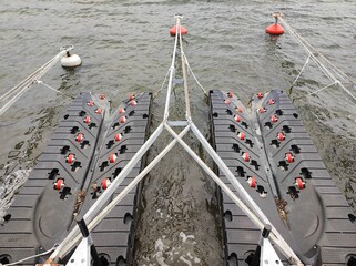 Two pontoons, a floating craft in the gray water