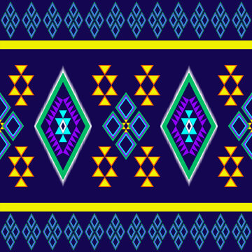 Traditional seamless tribal geometric pattern with colorful diamond and triangle motifs in purple, green, yellow, and orange on a dark navy background. Perfect for textile, fabric, wallpaper, and digi