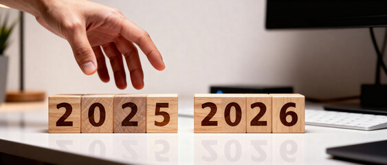 Hand reaching for wooden blocks displaying the years of twenty twenty five and twenty twenty six 2026