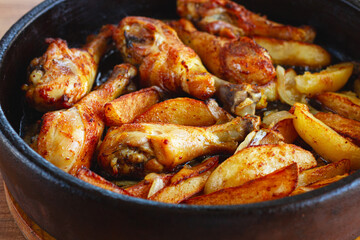 fried chicken drumsticks with potato slices, in a clay pan, baked in the oven, with spices, homemade, no people,