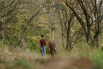 Obraz premium An authentic, candid moment as a couple walks along a leaf studded path in a quiet autumn wood, conveying credible connection and natural ease under soft light.