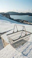 A metal shopping basket sits on a snowcovered surface with a scenic view of a lake and distant mountains, creating a juxtaposition of commerce and nature