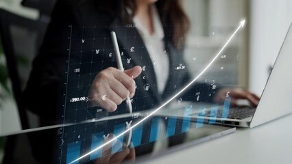 A business professional examines financial data on a laptop, highlighting growth trends with a...