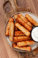 fried spring rolls with cheese, on a wooden background, with cream sauce, no people,