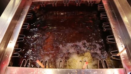 Deep-frying corn dogs in hot bubbling oil, showing intense heat, texture, and street-food cooking process with vibrant reflections and sizzling motion.