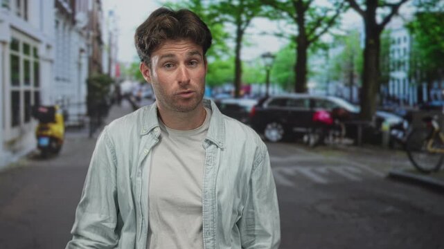 Man with hands covering mouth on a city street, glancing sideways and holding a muffled expression; shock silence.