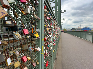 Porto, Portugal - September 15, 2025: Colorful love locks attached to a fence on a bridge with cloudy sky and cityscape in the background