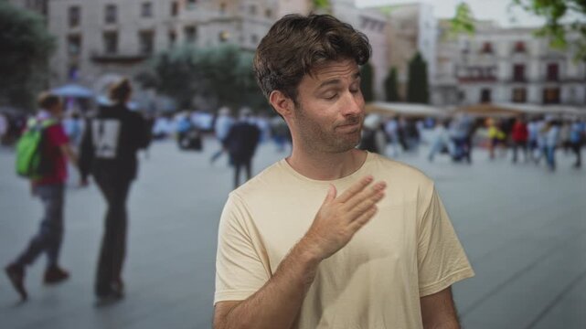 Man with hand on chest on crowded street in front of plaza buildings, gesture of apology and modesty while facing camera; sincere regret.