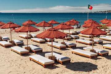 Empty sun beds with umbrellas on the public beach in Estoril, Portugal.