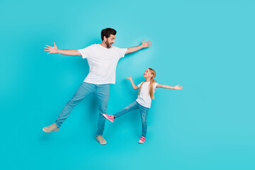 Father and daughter enjoying playful moments in casual attire against a bright teal background showcasing family bonding