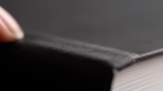 Close-up of human finger gently touching dark book cover