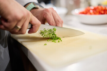 Professional chef chopping spring onions in kitchen