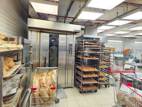 Busy Commercial Bakery Kitchen With Industrial Oven, Bread Racks, and Shopping Carts