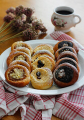 Traditional Czech festive kolache with apple, curd cheese and poppy seed filling sprinkled with powdered sugar served on plate with coffee cup and dried allium bouquet, sweet homemade bakery pastry