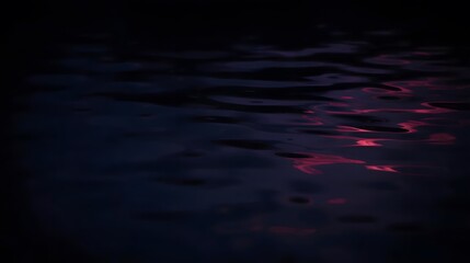 A mesmerizing view of dark waters, with crimson highlights dancing on the gentle, rippling surface.