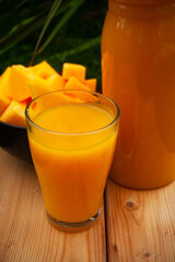 Harvesting fresh pumpkin juice displayed in a glass and pitcher on a wooden board close-up