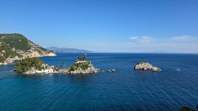 Panoramic seascape of Parga Greece with islands, clear Ionian Sea, coastal rocks and green hills. Famous tourist destination and summer holiday landscape in Epirus region.