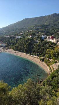 Panoramic view of Valtos Beach in Parga Greece. Sandy coast, turquoise Ionian Sea, green hills and sunbeds create perfect summer holiday travel destination photo in Epirus.