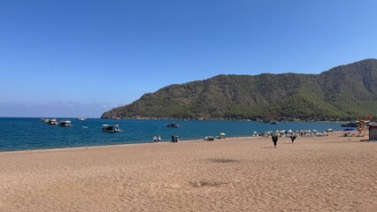 Pleasure boats anchored in the calm, vibrant turquoise waters of a secluded Mediterranean cove, surrounded by rugged cliffs and Taurus Mountains in Antalya, Turkey