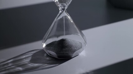 Glass hourglass with black sand and dramatic shadow - time management concept - Powered by Adobe