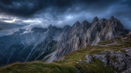 Fototapeta premium The sky is dark and cloudy, and the mountains are covered in snow. The scene is serene and peaceful, with the mountains towering over the landscape
