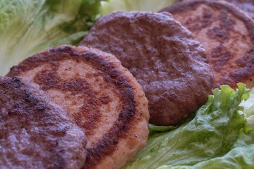 Grilled beef and chicken patties on lettuce leaves, homemade burger concept