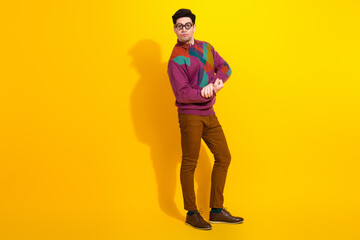 Fototapeta premium Young man with trendy glasses posing confidently in colorful sweater against a vibrant yellow background