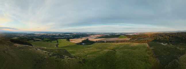 Aerial panoramic view of countryside fields and green hills at sunset. Beautiful rural landscape and nature background. Beecraigs Country Park, West Lothian, Scotland