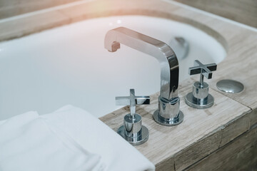 Bathtub in hotel. Modern Bathroom Sink Faucet with Stylish Taps and Soft Towels next to an Elegant Bathtub in a Relaxing Spa Environment