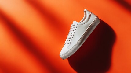 White sneaker floating in mid-air over orange background