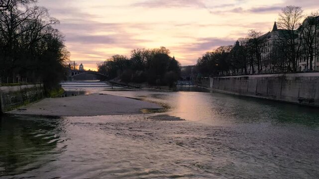 4K Drohnenflug &uuml;ber die Isar in M&uuml;nchen bei Sonnenuntergang mit Alpenpanorama und Skyline mit Deutschem Museum, M&uuml;llerschem Volksbad, Gasteig, Maximilianbr&uuml;cke und St. Lukas.