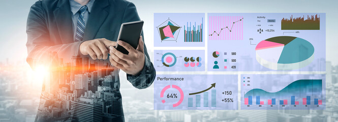 A business professional uses a smartphone while engaging with data analytics charts in a modern...