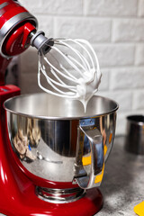 Red stand mixer with white cream. and stainless steel bowl. Cooking preparation.
