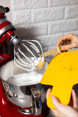 Chef's hands pouring vanilla beans in the red mixer. Close-up on orange cut board