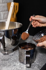 Closeup of woman  pour cocoa powder into mixing bowl with baking ingredients.