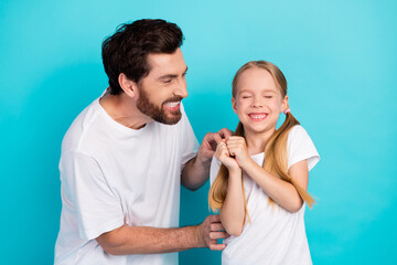 Father playfully interacts with young daughter enjoying a joyful bonding moment against a teal...