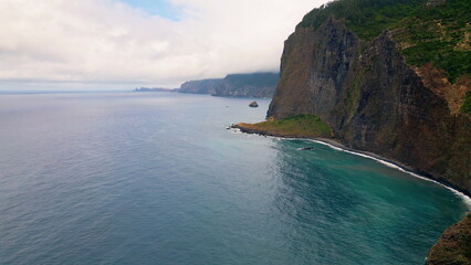 Obraz premium Idyllic lagune cloudy day aerial view. Stone cliff rising over blue ocean water.
