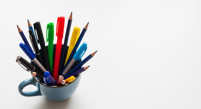 Colorful pens and pencils in a cute blue mug create a vibrant, creative workspace feel with blank space for text or graphics - perfect for back to school