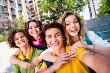 A group of cheerful young friends posing together outdoors during a sunny day, embracing and enjoying their friendship