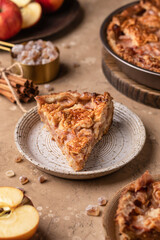 Slice of homemade Apple Pie with fresh apples on brown background close up. Thanksgiving traditional dessert, autumn baking, recipe