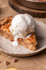 Slice of homemade Apple Pie with with a scoop of ice cream on brown background close up. Thanksgiving traditional dessert, autumn baking, recipe