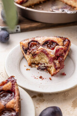 Homemade The New York Times plum cake. Slice of autumn fruit pie in a plate on beige textured background. Home cooking, recipe