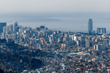 Obraz premium A cityscape with tall buildings and a blue sky. Panorama of Batumi from the mountains. Skyscrapers and buildings.