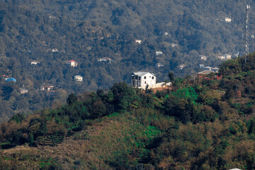 Fototapeta premium Rural area in Batumi. Rural houses located on the slopes of the mountains. One-storey, two-storey and three-storey houses are surrounded by tall green trees.
