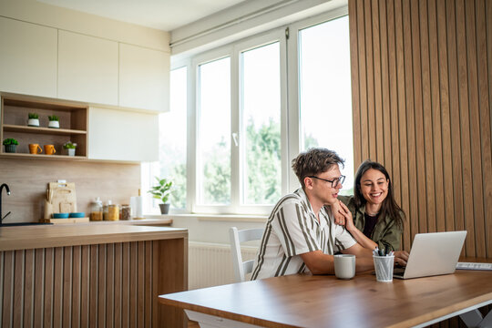Couple working on laptop in modern home kitchen