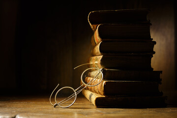 Vintage round spectacles with stack of antique books. A pile of old books on wooden table. Vintage still life, education concept