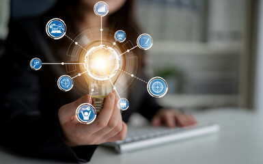 A business professional holds a glowing light bulb symbolizing innovation, surrounded by virtual icons. This image captures the essence of creativity and technology in a modern workspace. Crux